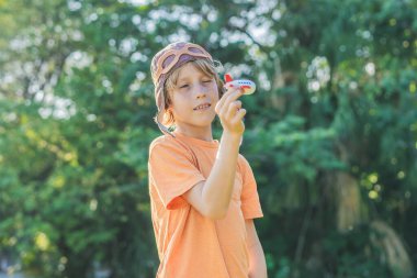 Pilot şapkası takan bir çocuk oyuncak bir uçakla çimlerde koşuyor, maceralar hayal ediyor. Çocukluk, hayal gücü ve özgürlük kavramı..