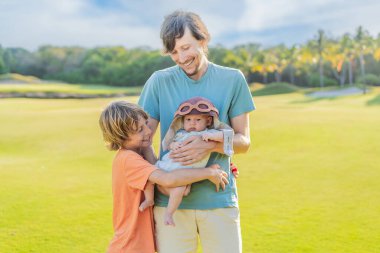 Baba, oğul ve çayır üzerinde yeni doğmuş bir bebek. Pilot şapkası takan bebek havacılık hayallerini sembolize ediyor. Aile bağı kavramı, geleceğin pilotu ve çocukluk arzusu..