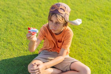 Pilot şapkası takan bir çocuk oyuncak bir uçakla çimlerde koşuyor, maceralar hayal ediyor. Çocukluk, hayal gücü ve özgürlük kavramı..