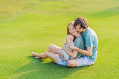 Yeni doğmuş bebekleriyle parktaki çayırda sevgi dolu ebeveynler. Mutlu aile doğanın tadını çıkarıyor, bağ kuruyor ve dışarıda huzurlu anlar yaşıyor. Ebeveynlik, sevgi ve aile bağları kavramı.