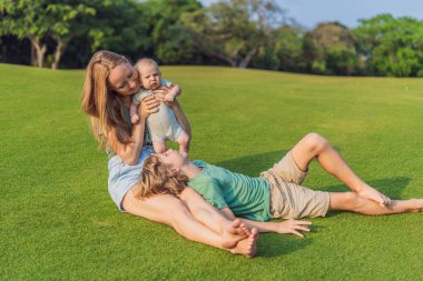 Anne, büyük oğul ve parkta bir çayırda yeni doğmuş bebek. Aile, doğada birlikte kaliteli zaman geçirir. Ebeveynlik, sevgi ve aile bağı kavramı.