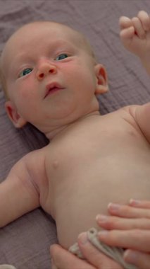 Bir anne yeni doğmuş bebeğine nazikçe masaj yapar ve bebekler için cilt yağı sürer. Bebeklerin rahatlığını, rahatlığını ve sağlıklı cildini destekleyen hassas bir bağ ve bakım anı. Yavaş çekim videosu