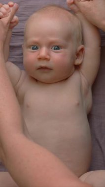 Bir anne yeni doğmuş bebeğiyle nazikçe jimnastik yapar, bebek kollarını ve bacaklarını hafifçe hareket ettirir. Bağ kurmayı, esnekliği ve bebek refahını teşvik eden hassas ve besleyici bir faaliyet.