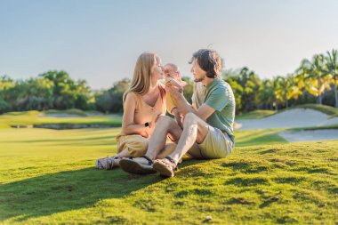 Yeni doğmuş bebekleriyle parktaki çayırda sevgi dolu ebeveynler. Mutlu aile doğanın tadını çıkarıyor, bağ kuruyor ve dışarıda huzurlu anlar yaşıyor. Ebeveynlik, sevgi ve aile bağları kavramı.