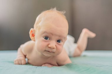 Bir aylık bir bebek karnının üstünde yatıyor ve tuhaf bir şekilde çevreyi gözlemliyor. Boyun dayanıklılığı, bilişsel gelişim ve erken keşif için bebek midesi zamanı. Ebeveynlik ve yeni doğan büyüme kavramı.