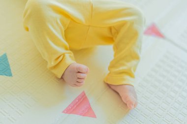 Sarı şapkalı sevimli bebek oyun hasırının üzerinde yatıyor. Yumuşak dokuları ve parlak renkleriyle yeni doğmuş gibi. Bebek gelişimi, duyusal oyun ve erken çocukluk kavramı..