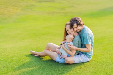 Yeni doğmuş bebekleriyle parktaki çayırda sevgi dolu ebeveynler. Mutlu aile doğanın tadını çıkarıyor, bağ kuruyor ve dışarıda huzurlu anlar yaşıyor. Ebeveynlik, sevgi ve aile bağları kavramı.