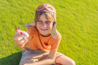 Pilot şapkası takan bir çocuk oyuncak bir uçakla çimlerde koşuyor, maceralar hayal ediyor. Çocukluk, hayal gücü ve özgürlük kavramı..