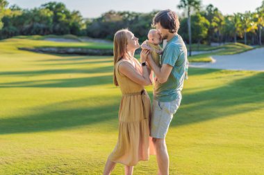Yeni doğmuş bebekleriyle parktaki çayırda sevgi dolu ebeveynler. Mutlu aile doğanın tadını çıkarıyor, bağ kuruyor ve dışarıda huzurlu anlar yaşıyor. Ebeveynlik, sevgi ve aile bağları kavramı.