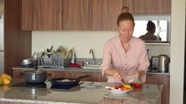 Genç bir kadın mutfakta yemek pişiriyor ve lezzetli bir ev yemeği hazırlamaya odaklanıyor. Sıcacık bir ortamda ev yapımı, yaratıcılık ve aşçılık keyfi.