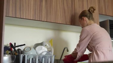 Genç bir kadın mutfakta bulaşıkları yıkıyor, temizlik ve düzene odaklanıyor. Basit ve uyumlu bir ev yapımı, ev bakımı ve düzenli bir ev ortamı.