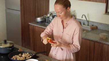 Genç bir kadın mutfakta yemek pişiriyor ve lezzetli bir ev yemeği hazırlamaya odaklanıyor. Sıcacık bir ortamda ev yapımı, yaratıcılık ve aşçılık keyfi.