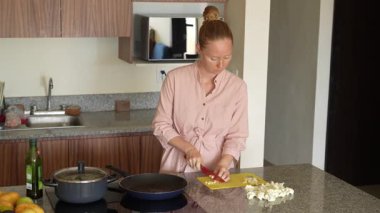 Genç bir kadın mutfakta yemek pişiriyor ve lezzetli bir ev yemeği hazırlamaya odaklanıyor. Sıcacık bir ortamda ev yapımı, yaratıcılık ve aşçılık keyfi.