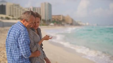 Romantik orta yaşlı çift kumsalda huzurlu bir akşamın tadını çıkarıyor. Olgun ilişkiler ve yavaş yaşam tarzı için aşk, bağlantı ve birliktelik kavramı