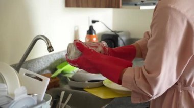 Genç bir kadın mutfakta bulaşıkları yıkıyor, temizlik ve düzene odaklanıyor. Basit ve uyumlu bir ev yapımı, ev bakımı ve düzenli bir ev ortamı.