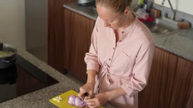 Genç bir kadın mutfakta yemek pişiriyor ve lezzetli bir ev yemeği hazırlamaya odaklanıyor. Sıcacık bir ortamda ev yapımı, yaratıcılık ve aşçılık keyfi.