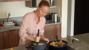 Genç bir kadın mutfakta yemek pişiriyor ve lezzetli bir ev yemeği hazırlamaya odaklanıyor. Sıcacık bir ortamda ev yapımı, yaratıcılık ve aşçılık keyfi.