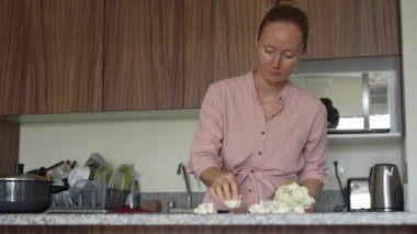 Genç bir kadın mutfakta yemek pişiriyor ve lezzetli bir ev yemeği hazırlamaya odaklanıyor. Sıcacık bir ortamda ev yapımı, yaratıcılık ve aşçılık keyfi.