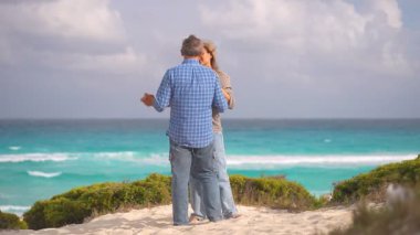 Romantik orta yaşlı çift kumsalda huzurlu bir akşamın tadını çıkarıyor. Olgun ilişkiler ve yavaş yaşam tarzı için aşk, bağlantı ve birliktelik kavramı