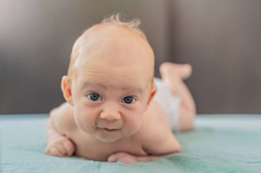 Bir aylık bir bebek karnının üstünde yatıyor ve tuhaf bir şekilde çevreyi gözlemliyor. Boyun dayanıklılığı, bilişsel gelişim ve erken keşif için bebek midesi zamanı. Ebeveynlik ve yeni doğan büyüme kavramı.