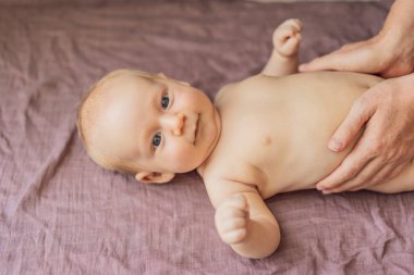 Yeni doğmuş bebek yumuşak bir battaniyenin üzerinde yatarken anne küçük bebek uzuvlarını nazikçe çalıştırıyor. Erken gelişim, bağlanma ve bebek bakımı kavramı.