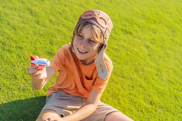 Pilot şapkası takan bir çocuk oyuncak bir uçakla çimlerde koşuyor, maceralar hayal ediyor. Çocukluk, hayal gücü ve özgürlük kavramı..