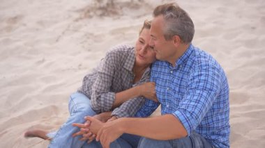 Romantik orta yaşlı çift kumsalda huzurlu bir akşamın tadını çıkarıyor. Olgun ilişkiler ve yavaş yaşam tarzı için aşk, bağlantı ve birliktelik kavramı