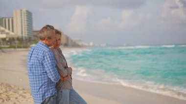 Romantik orta yaşlı çift kumsalda huzurlu bir akşamın tadını çıkarıyor. Olgun ilişkiler ve yavaş yaşam tarzı için aşk, bağlantı ve birliktelik kavramı