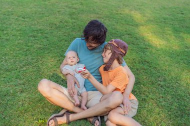 Baba ve iki oğlu parkta, büyük çocuk pilot şapkası takıyor ve bebek izlerken oyuncak bir uçak tutuyor. Çocukluk, bağ ve aile macerası konsepti.