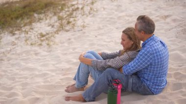 Romantik orta yaşlı çift kumsalda huzurlu bir akşamın tadını çıkarıyor. Olgun ilişkiler ve yavaş yaşam tarzı için aşk, bağlantı ve birliktelik kavramı