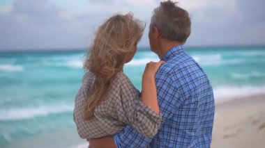 Romantik orta yaşlı çift kumsalda huzurlu bir akşamın tadını çıkarıyor. Olgun ilişkiler ve yavaş yaşam tarzı için aşk, bağlantı ve birliktelik kavramı