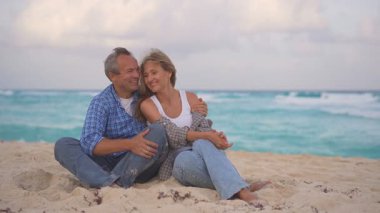 Romantik orta yaşlı çift kumsalda huzurlu bir akşamın tadını çıkarıyor. Olgun ilişkiler ve yavaş yaşam tarzı için aşk, bağlantı ve birliktelik kavramı