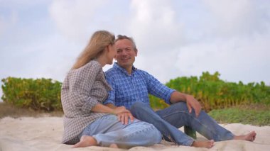 Romantik orta yaşlı çift kumsalda huzurlu bir akşamın tadını çıkarıyor. Olgun ilişkiler ve yavaş yaşam tarzı için aşk, bağlantı ve birliktelik kavramı