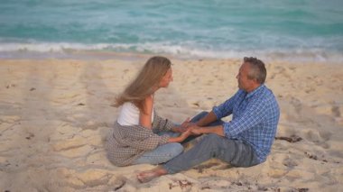 Romantik orta yaşlı çift kumsalda huzurlu bir akşamın tadını çıkarıyor. Olgun ilişkiler ve yavaş yaşam tarzı için aşk, bağlantı ve birliktelik kavramı