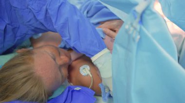 Cerrah sezaryen ameliyatını tamamlarken yeni doğmuş bir bebek anne göğsüne yerleştirilir. Annelik bağı, aşk ve doğumdan sonraki ilk kucaklaşma.