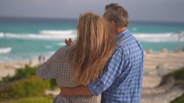 Romantik orta yaşlı çift kumsalda huzurlu bir akşamın tadını çıkarıyor. Olgun ilişkiler ve yavaş yaşam tarzı için aşk, bağlantı ve birliktelik kavramı