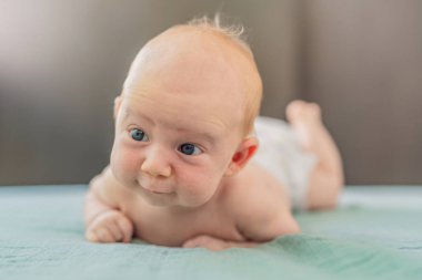 Bir aylık bir bebek karnının üstünde yatıyor ve tuhaf bir şekilde çevreyi gözlemliyor. Boyun dayanıklılığı, bilişsel gelişim ve erken keşif için bebek midesi zamanı. Ebeveynlik ve yeni doğan büyüme kavramı.