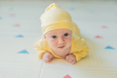 Bir aylık bir bebek karnının üstünde yatıyor ve tuhaf bir şekilde çevreyi gözlemliyor. Boyun dayanıklılığı, bilişsel gelişim ve erken keşif için bebek midesi zamanı. Ebeveynlik ve yeni doğan büyüme kavramı.