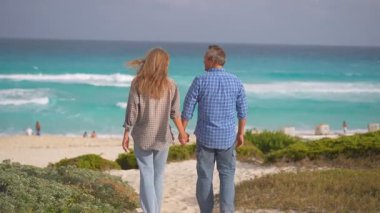 Romantik orta yaşlı çift kumsalda huzurlu bir akşamın tadını çıkarıyor. Olgun ilişkiler ve yavaş yaşam tarzı için aşk, bağlantı ve birliktelik kavramı