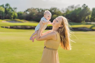 Anne ve yeni doğmuş bebek parkta bir çayırda. Doğadaki hassas bağ anı. Ebeveynlik, sevgi ve aile bağları kavramı.