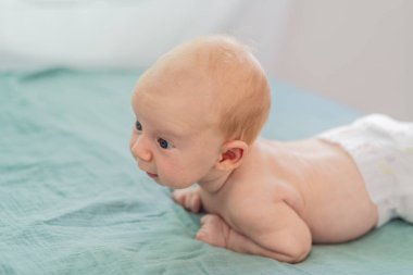 Bir aylık bir bebek karnının üstünde yatıyor ve tuhaf bir şekilde çevreyi gözlemliyor. Boyun dayanıklılığı, bilişsel gelişim ve erken keşif için bebek midesi zamanı. Ebeveynlik ve yeni doğan büyüme kavramı.