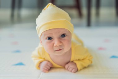 Bir aylık bir bebek karnının üstünde yatıyor ve tuhaf bir şekilde çevreyi gözlemliyor. Boyun dayanıklılığı, bilişsel gelişim ve erken keşif için bebek midesi zamanı. Ebeveynlik ve yeni doğan büyüme kavramı.