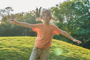 Pilot şapkası takan bir çocuk oyuncak bir uçakla çimlerde koşuyor, maceralar hayal ediyor. Çocukluk, hayal gücü ve özgürlük kavramı..