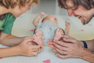 Baba, oğul ve yeni doğan bebek sıcak bir kreşte yerde yatıyorlar ve yeni aile üyelerinin gelişini kutluyorlar. Ebeveynlik, bağlılık ve aile sevgisi kavramı.