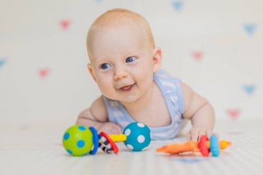Evdeki yumuşak bir bebek minderinde renkli çıngıraklarla oynayan sevimli bir bebek. Erken gelişim kavramı, duyusal oyun ve bebekler için güvenli öğrenme ortamı.