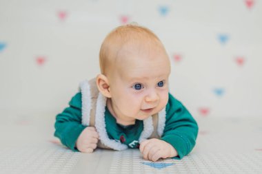 Noel süveteri, kot pantolon ve kış tatiline hazır, tüylü bir yelek giymiş sevimli bir bebek. Şenlikli bebek modası ve rahat tatil anları konsepti.