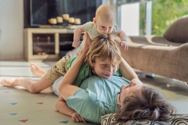 Baba, oğul ve yeni doğan bebek sıcak bir kreşte yerde yatıyorlar ve yeni aile üyelerinin gelişini kutluyorlar. Ebeveynlik, bağlılık ve aile sevgisi kavramı.