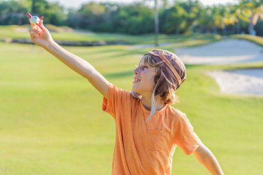 Pilot şapkası takan bir çocuk oyuncak bir uçakla çimlerde koşuyor, maceralar hayal ediyor. Çocukluk, hayal gücü ve özgürlük kavramı..