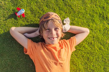 Pilot şapkası takan bir çocuk oyuncak bir uçakla çimlerde koşuyor, maceralar hayal ediyor. Çocukluk, hayal gücü ve özgürlük kavramı..
