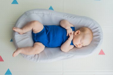 Tombul 3 aylık bebek evdeki rahat bir bebek yuvasında huzur içinde uyuyor. Sıcak ve besleyici bir ortamda bebek konforu, güvenlik ve erken gelişim kavramı.